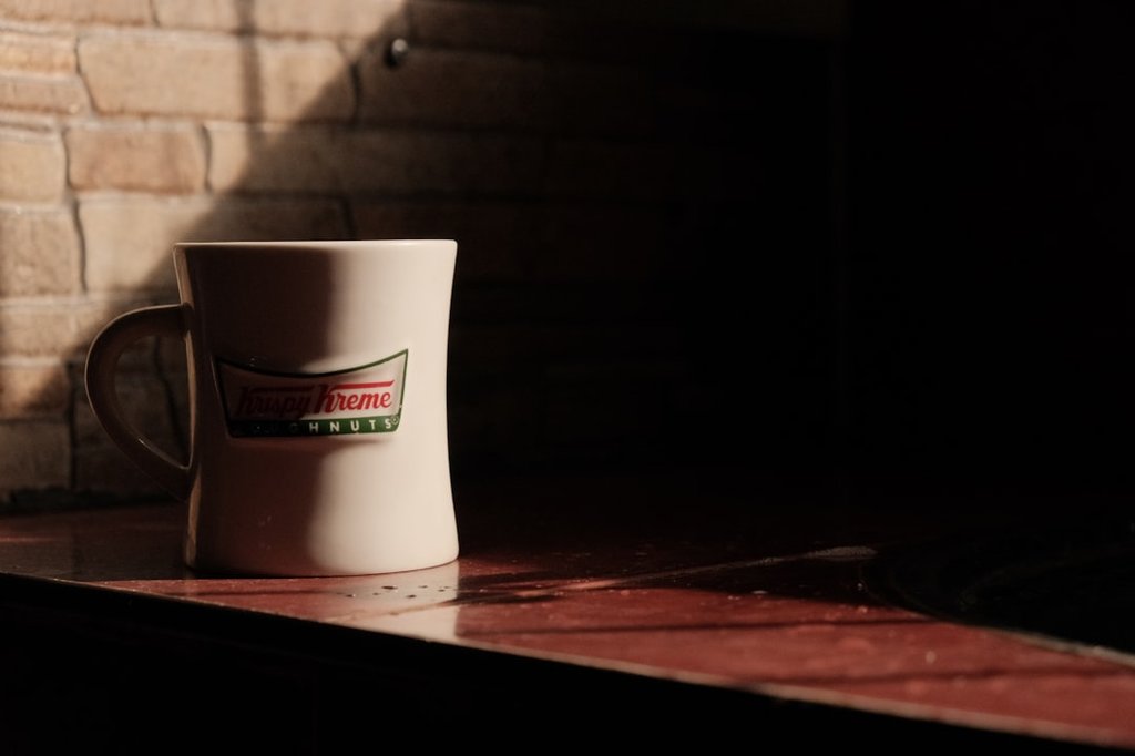 Krispy Kreme - a coffee cup sitting on top of a counter